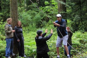 During a visit to the Evergreen challenge course, teams must work together to accomplish tasks such as moving all team members along a thin wire.