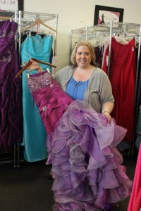 Lori Kenyon, one of the owners of the non-profit organization, displays one of over 2,000 dresses available for rent.