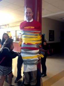 To raise awareness and money to aid Marysville Pilchuck High School, Mr. Woods challenged the student body to pay $1 each to tape him to a post. When the chair was removed at the end of lunch, enough tape had been wrapped that he stayed.