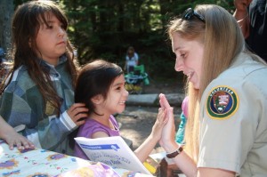 Education intern Emily Frost swears in a Jr. Ranger at the Cougar Rock Campground National Park Service. Photo by Kevin Bacher.