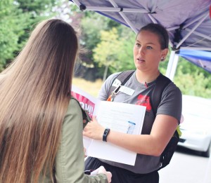 An orientation leader gives a new student her “swag bag” and some useful information for upcoming orientation activities.