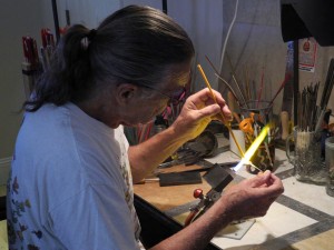 Ernie adds a different color  glass to the hot base bead. Photo Credit: Doris Faltys
