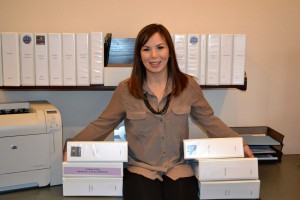 Keshia, surrounded by the many binders that contain the records she keeps for each HOA community.