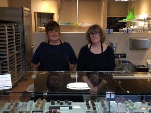 Deb Smith (left) and Cindy Uhrich stand behind the case full of their chocolates at their new downtown Olympia shop, Bittersweet Chocolates.