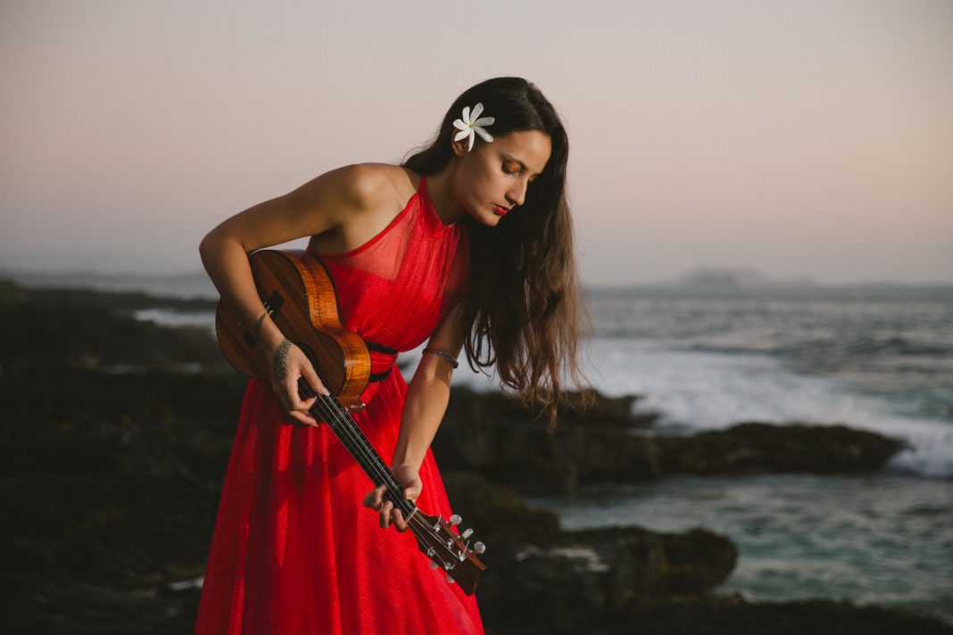 Taimane performing on beach in red dress