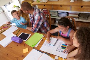 Parents Helping Children With Homework At Table