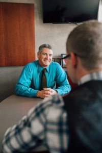 Jason Andrew sitting at desk with client