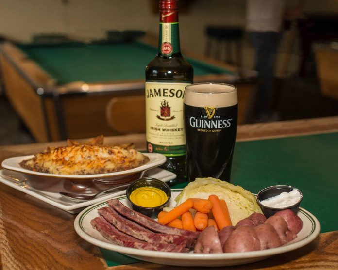 plate of corned beef and cabbage, with bottle of whiskey and glass of guinness