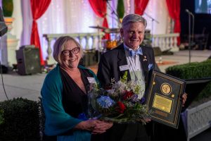 Dr Heynderickx and his wife Kathleen holding flowers and an award from the Saint Martin's Gala