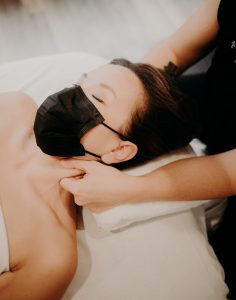 woman in a mask getting a shoulder massage