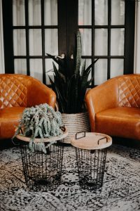Two orange leather chairs with a plant in the middle and two small tables in front in the reception room at Ballaura