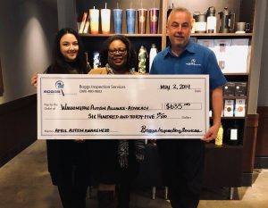 Dwayne Boggs and two ladies  holding a  large donation check to Washington Autism Alliance