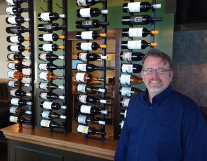 Cynara's owner, Christian Skilling, standing in front of a wall of wine