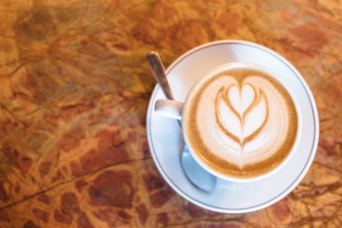 Latte in a white cup on a brown counter