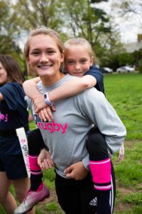 young girl piggybacking on another young girl at rugby practice