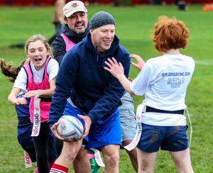 two adult guardians play rugby with young girls during Rugby Family Day