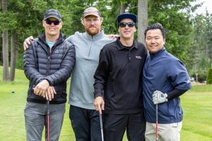 Four male golf players posing for photo on the green
