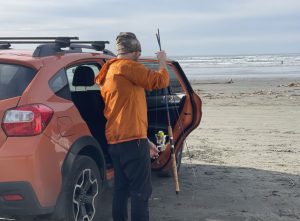 man getting fishing pole out of car at beach