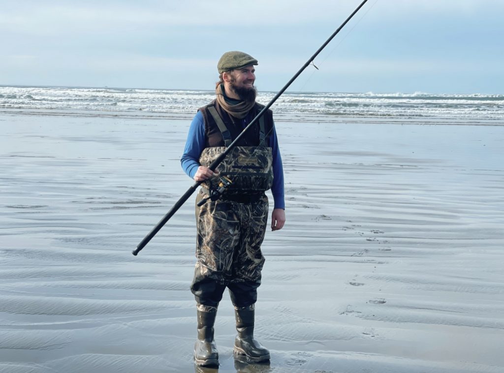 Man standing in ocean with waders and fishing pole