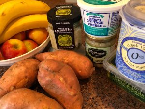 sweet potatoes, bananas, sauerkraut, cottage cheese  and yogurt on a counter 