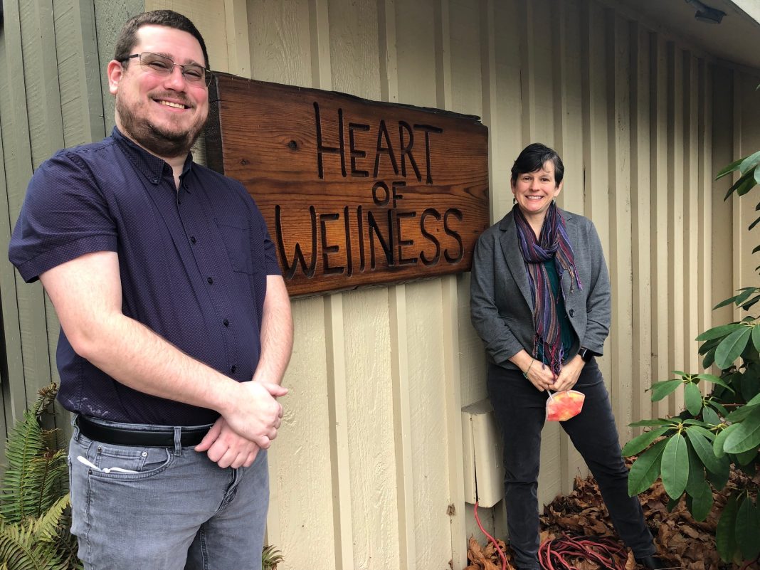 Ben Edwards, Heart of Wellness clinic manager, and Laura Woodworth, registered dietician nutritionist, standing by clinic sign