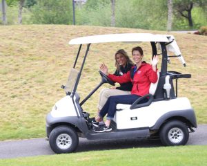 two golfers in a golf cart on a course