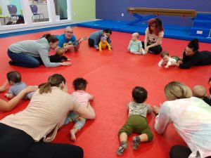 little children with their parents on a red mat doing stretches at The Little Gym Olympia