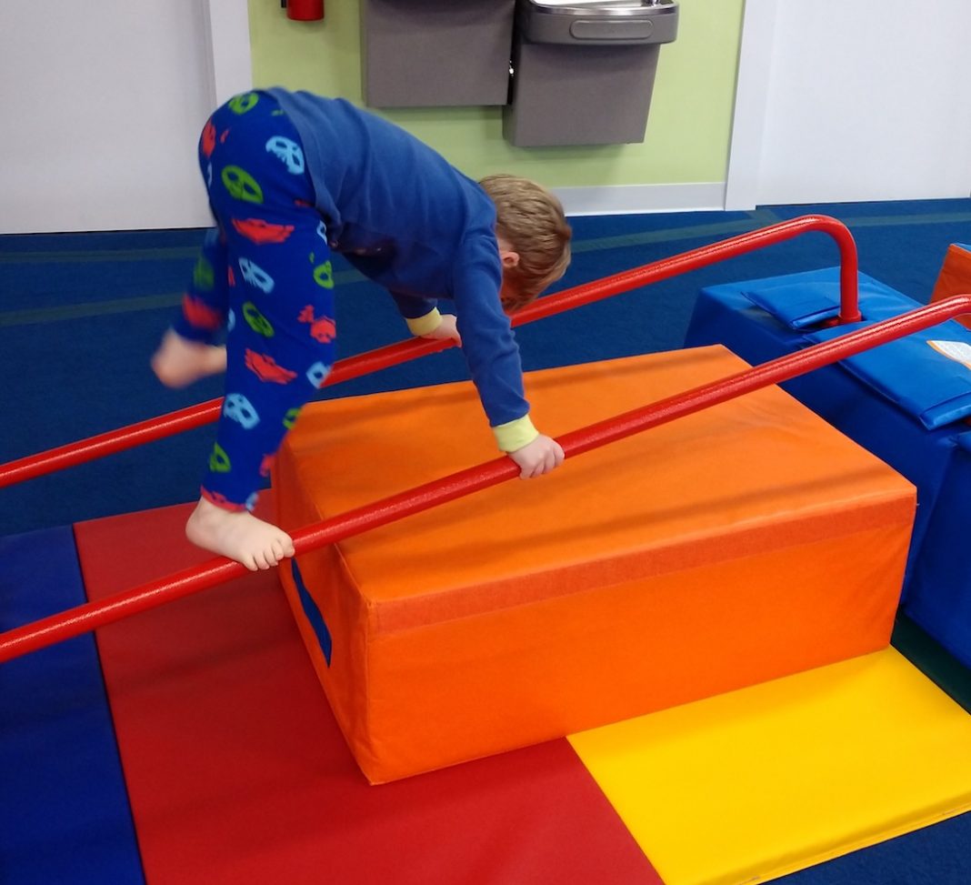 young child climbing up bars on a block at The Little Gym Olympia