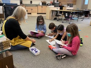 students sitting on the floor in a circle a teacher reading at a North Thurston School