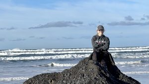 teen sitting on rock with ocean behind him