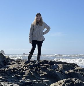 Adolescent în picioare pe o stâncă la plajă