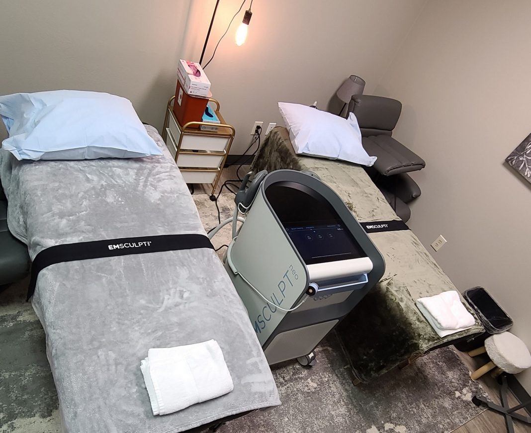 Patient room with beds and an Emsculpt machine at Rejuvenate IV Hydration & Wellness Center