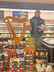 Thriftway worker standing with a table full of St. Patrick's Day food including beer, corned beef, and cabbage