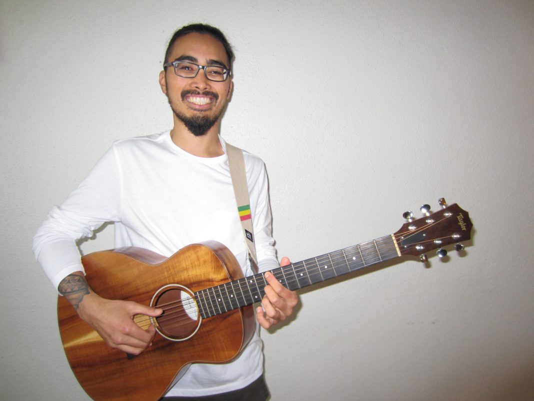 Matt Sablan 'Sabyu' holding a guitar against white background