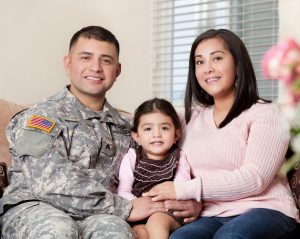 military man in fatigues with wife and daughter