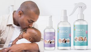 photo of a man holding and kissing an infant with bottles of Briotech next to him