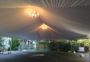 big white party tent with chandeliers hanging from it 