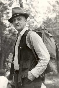 Earl Raymond Thoma standing with a hat and backpack