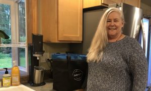 women standing by Farm to Fit delivery bag that is sitting on her kitchen counter