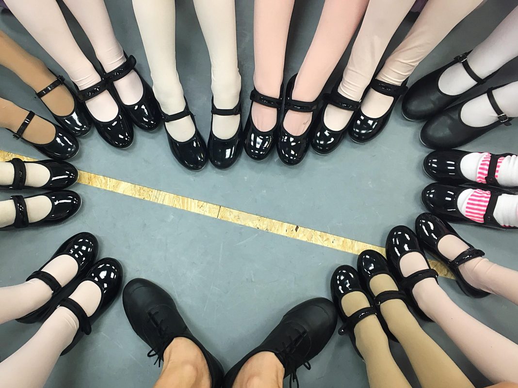 dozens of pairs of legs with dance shoes stepping forward to create a heart shape