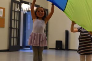 little girl holding a large parachute "tent" at South Sound Dance