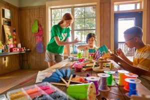  children and a YMCA worker doing crafts on a table