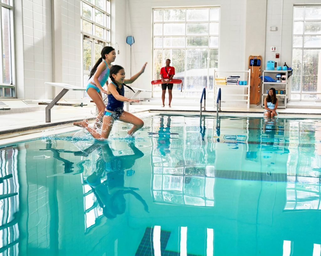 two children jumping into an indoor pool at the South Sound YMCA