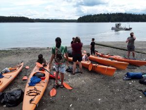 a bunch of kayaks and kids on the beach