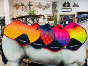 four brightly colored saddle blankets on a full size plastic horse at Tack Room Too