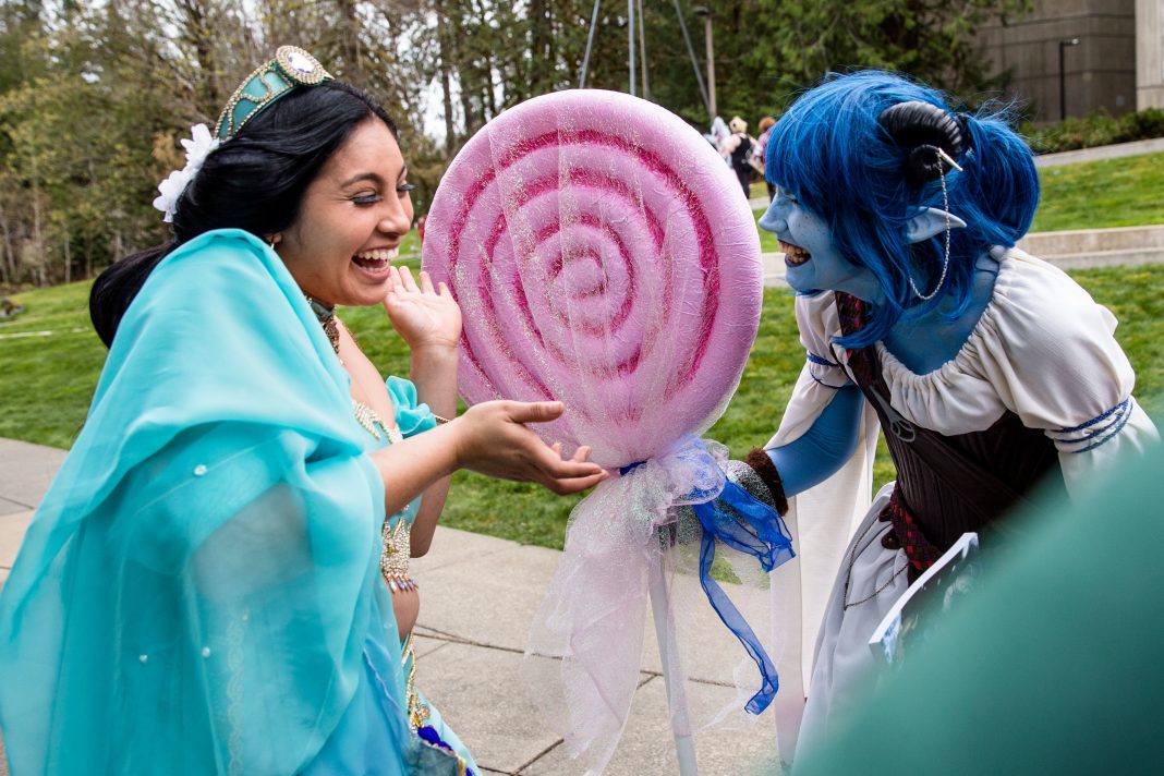 two people dressed as anime characters holding a huge fake lolipop