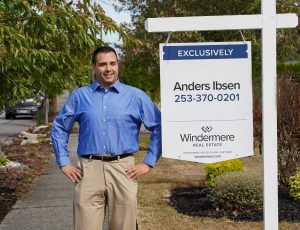 Anders Ibsen, real estate agent, standing next to windermere for sale sign