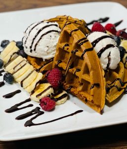 A liege waffle with ice cream, chocolate sauce and fruit from Waffle Craze