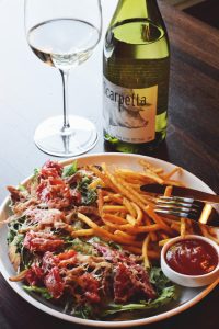 bottle of wine with a plate of food at Cynara