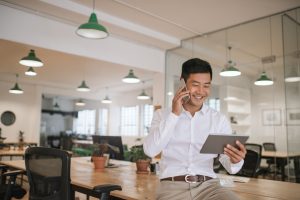 man in business shirt holding a tablet and talking on the phone in a modern kitchen